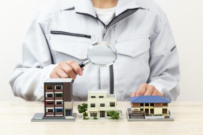 Hand observing a house model with a magnifying glass