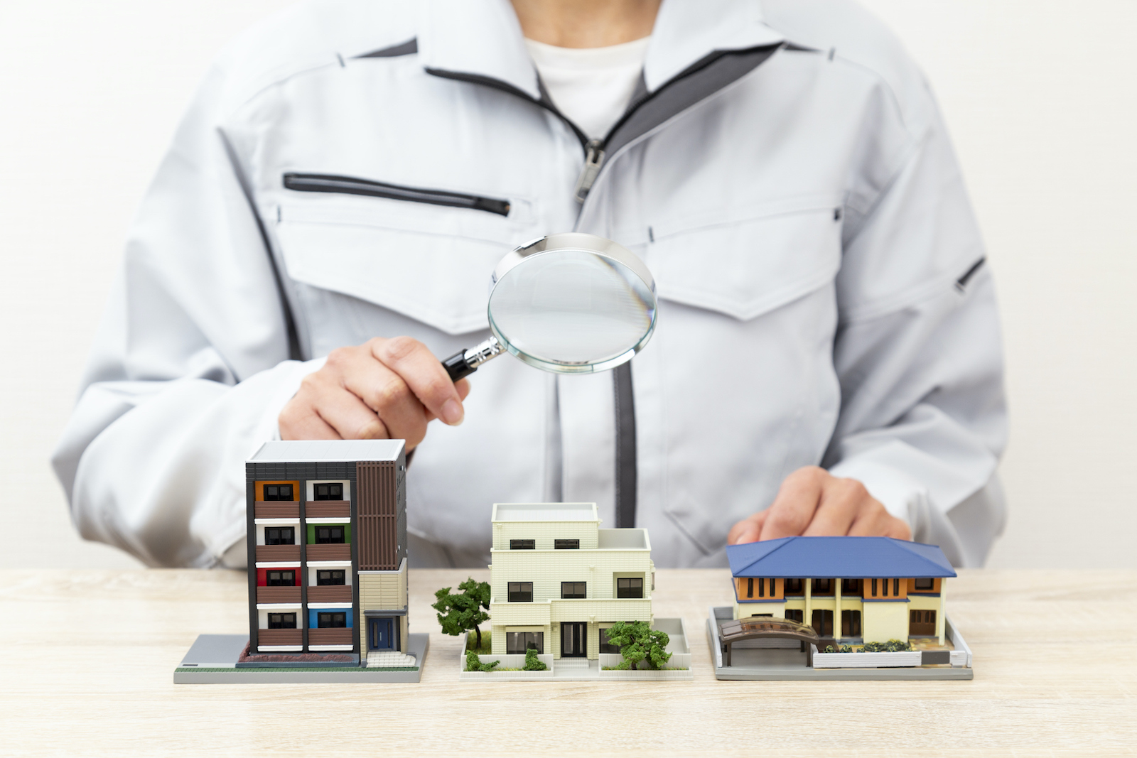 Hand observing a house model with a magnifying glass